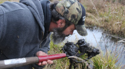 Craig Ritter checks the odor of a forkful of the Talmadge Creek bank.