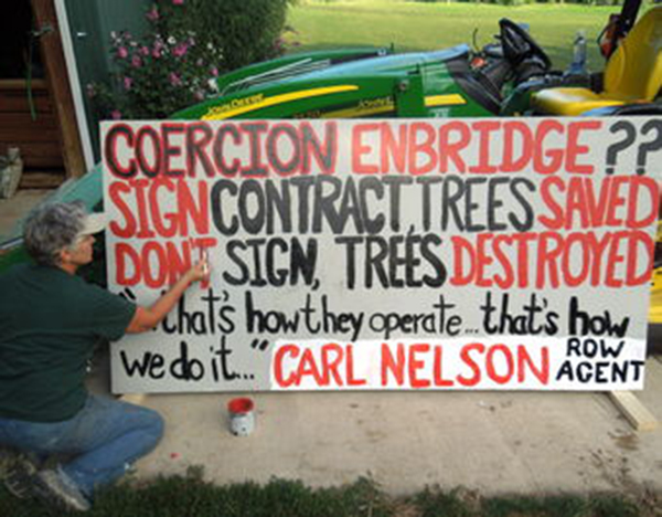Carol Brimhall painted and posted protest signs in front of her property.